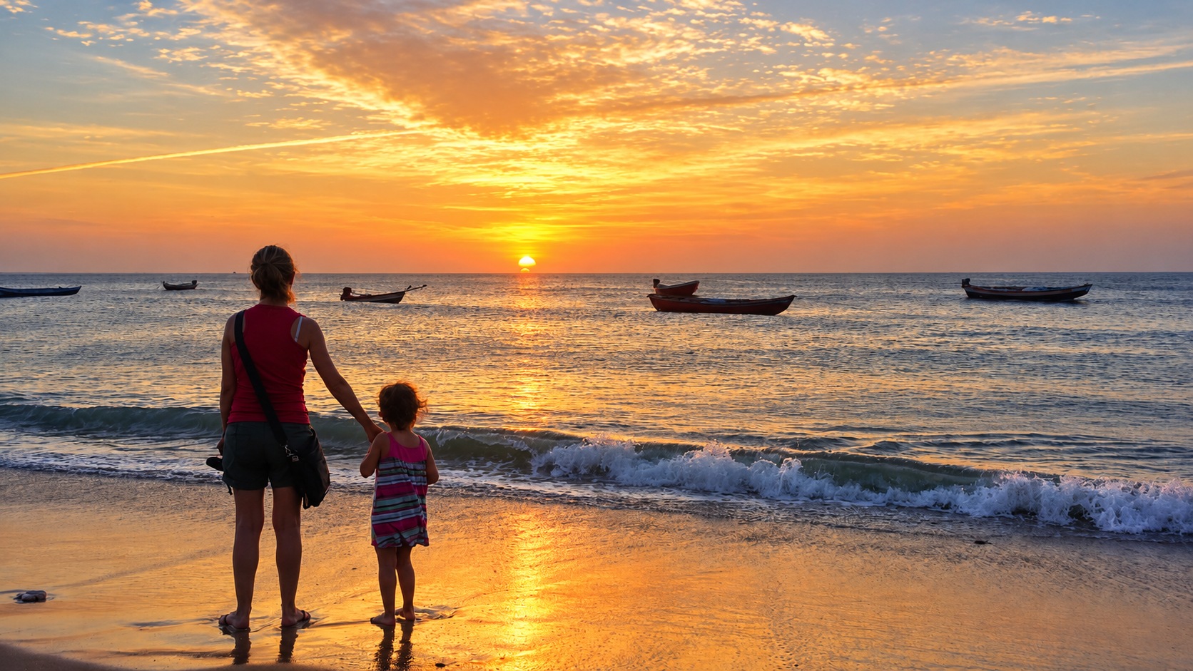 Mãe e criança de mãos dadas na praia ao pôr do sol