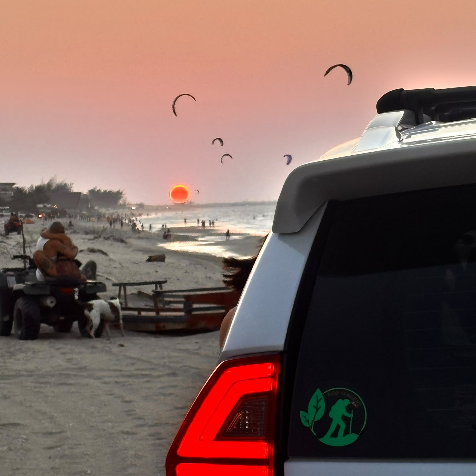 Pôr do sol na praia com kites e veículo Eco Viagens